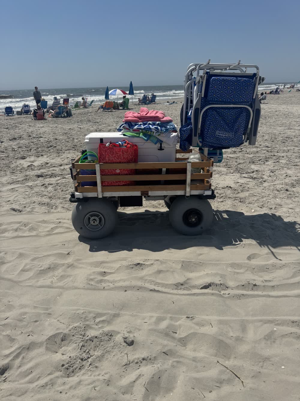 Side profile on open sand: cooler, bags, and chairs stacked for the day